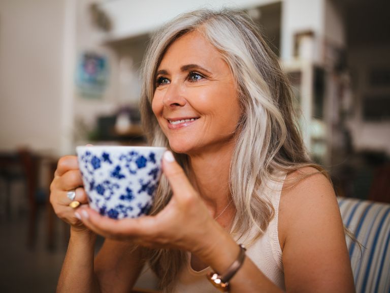 Middle-aged woman in her home smiling with a cup of tea